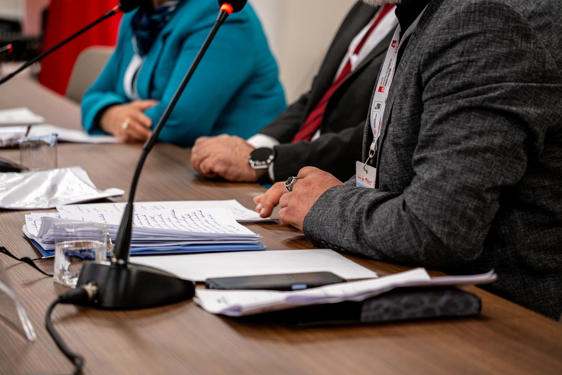 Delegates seated at a conference table with papers, name badges and microphones