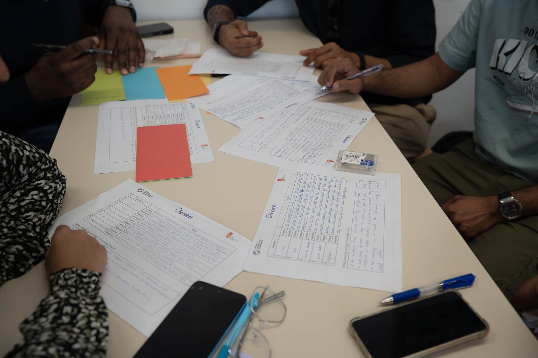 Delegates working through printed worksheets and coloured cards spread across a table